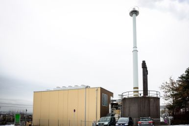 Energiezentrale im H 130. Braunes, viereckiges Gebäude neben einem dunkelbraunen, runden Gebäude, auf welchem mehrere Schornsteine stehen.