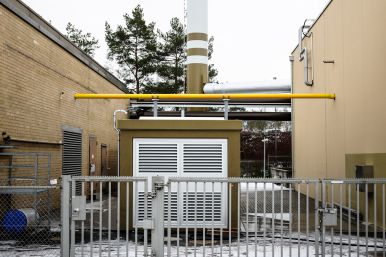 Energiezentrale im H 130. Braune Gebäude und ein hoher, weißer Schornstein.