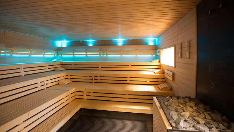 Innenasicht einer Holzsaune mit blauem Licht und Holzbänken