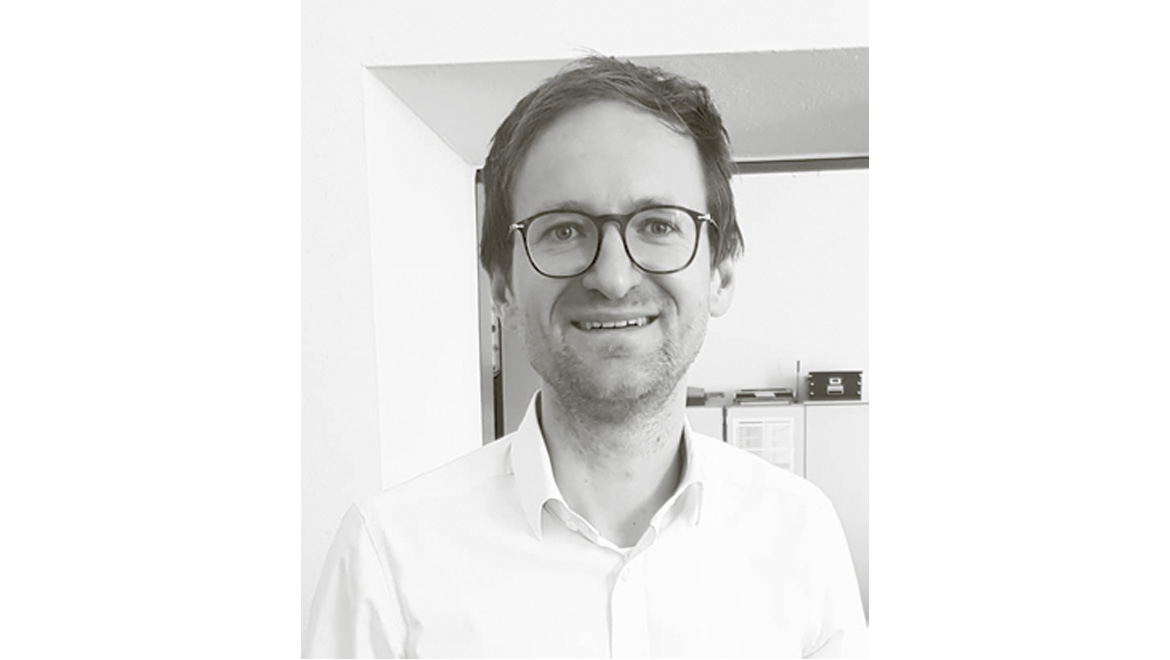 Ein Portrait von Prof. Bastian Schroeter, einem lächelnden Mann mit Brille und weißem Hemd.