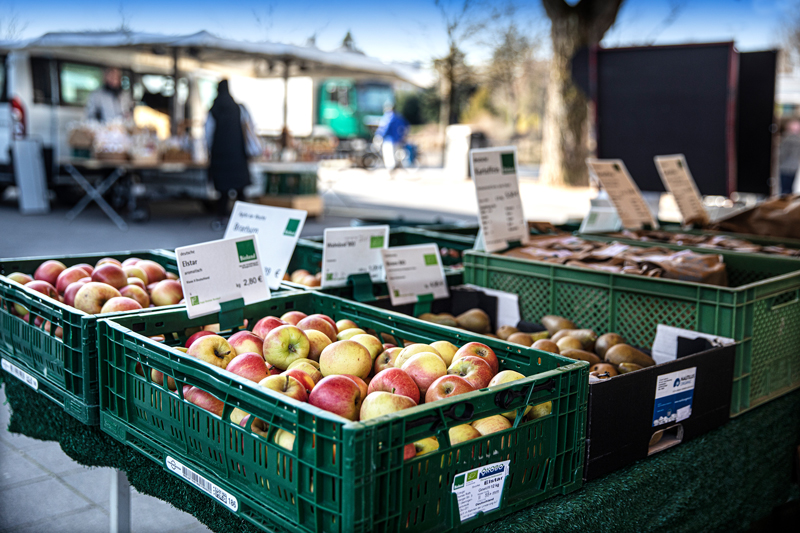 Obststand auf dem Wochenmarkt in Böblingen, mehrere grüne Kisten mit Äpfeln und weiterer Marktstand im Hintergrund